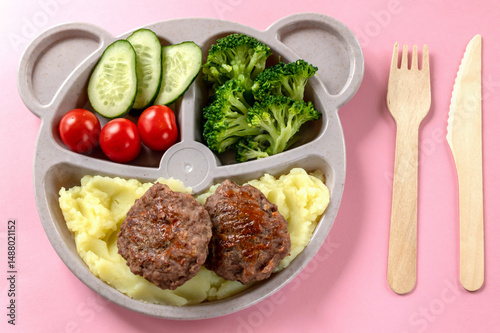 Baby food on a plate. Wooden fork and knife. Lunch or dinner option for a child.