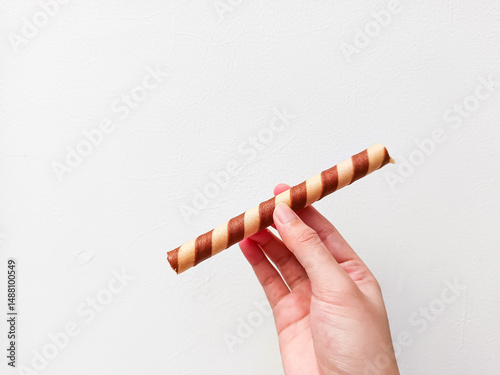 Crispy chocolate wafer roll held in hand against a clean white background—perfect for dessert brands, snack ads, or minimalist food packaging with a modern touch