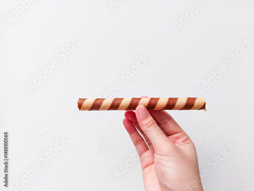 Crispy chocolate wafer roll held in hand against a clean white background—perfect for dessert brands, snack ads, or minimalist food packaging with a modern touch