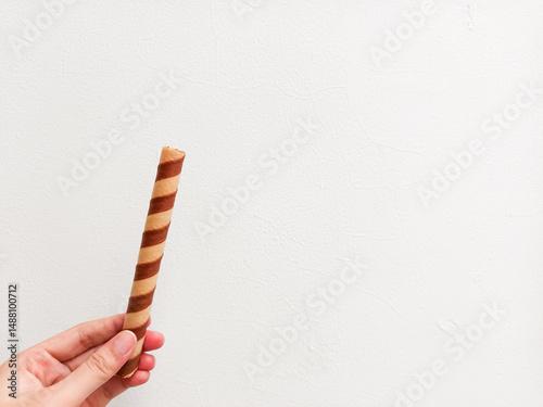 Crispy chocolate wafer roll held in hand against a clean white background—perfect for dessert brands, snack ads, or minimalist food packaging with a modern touch