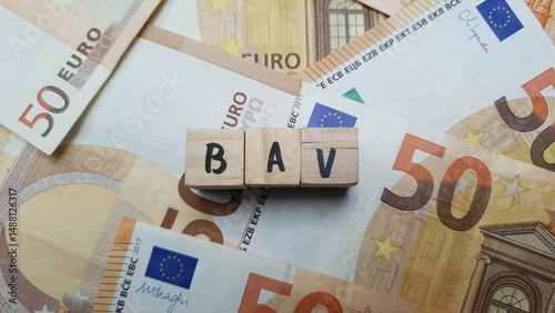 BAV acronym made of wooden letter cubes on pile of Euro banknotes. Betriebliche Altersvorsorge (Company Pension Scheme)