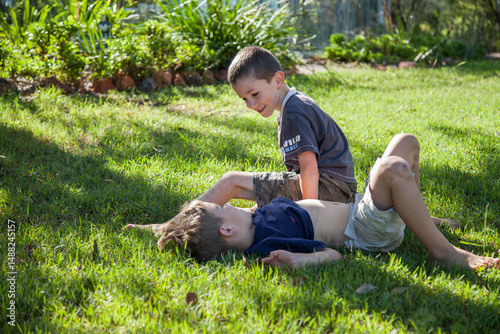 Two brothers tackling on the grass outside