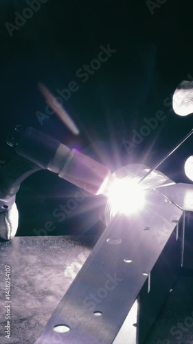Welding in progress with intense light and sparks. A close-up of a worker performing a welding task