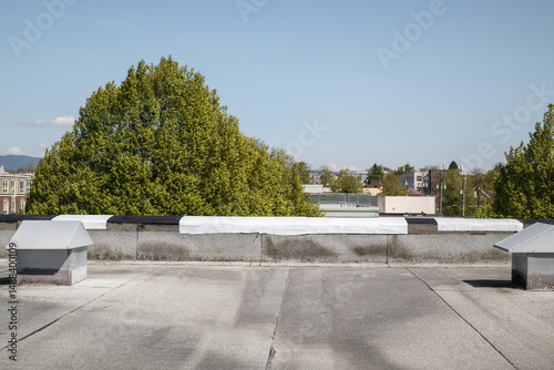 Self-adhered waterproof membrane on flat roof edge. Roof coping removed for temporary or permanent peel-and-stick waterproof membrane. 2-ply SBS or modified bitumen roofing system. Selective focus.
