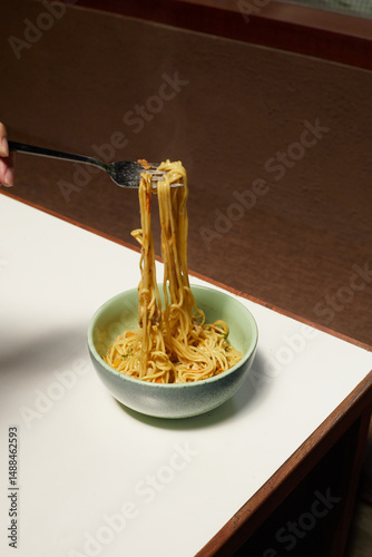 Fork Lifts Noodles From a Bowl at a Cozy Dining Setting