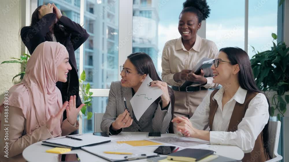Excited happy multiethnic women females team girls African American Caucasian Japanese Muslim hijab Arabian businesswomen analyzing statistic document paper graph celebrating success startup in office