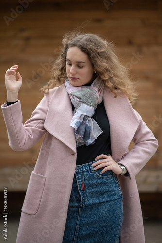 Portrait of a beautiful red-haired girl in a gray coat in a city park.