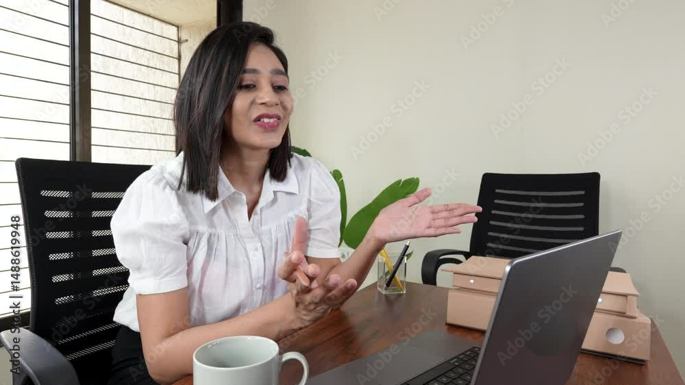 confident young Indian businesswoman smiling while explaining during a video call on her laptop confident young Indian businesswoman smiling while explaining during a video call on her laptop