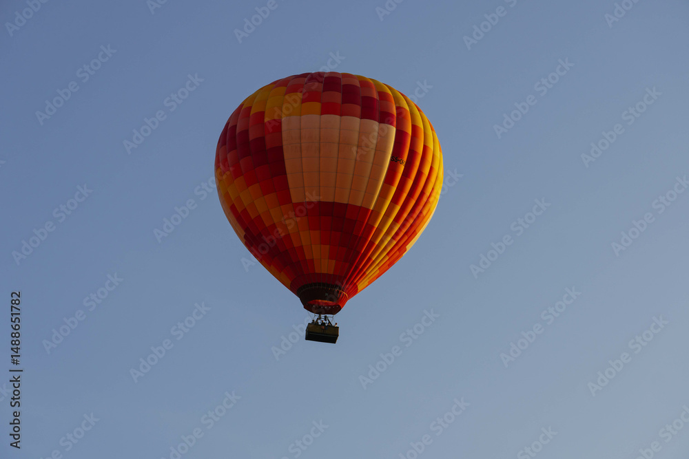 Fototapeta premium red orange hot air balloon at sunrise flying with mountains line behind minimalist