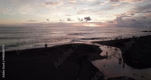 Drone shot of sunset in Bali. The river flows into the Pacific Ocean. People are having fun relaxing and having a nice time