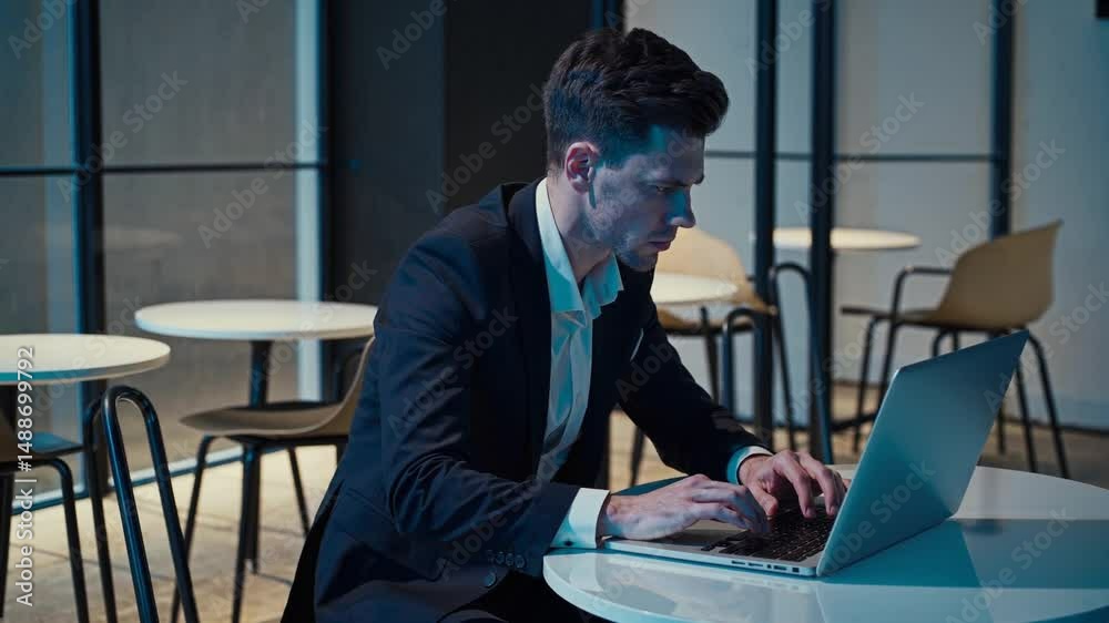 Homme en costume travaillant sur un ordinateur portable dans un espace calme et moderne

