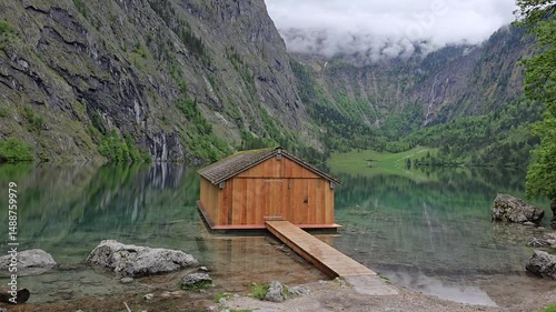 Wooden boathouse on the of Lake Obersee in Bavaria, Germany. Surrounded by dramatic cliffs and alpine greenery in Berchtesgaden National Park.