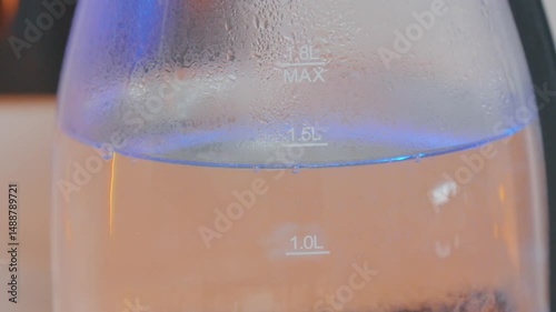 Clear glass water container with measurement markings displayed, showcasing condensation in a modern indoor setting