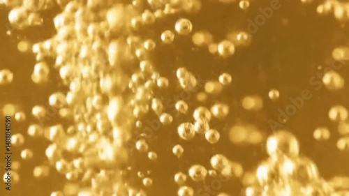 Close up video of golden liquid with many small bubbles floating and moving around