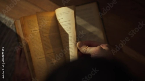 A person is browsing through the pages of an old book in a warm and cozy environment. The soft light highlights the text as they explore its content, evoking a sense of nostalgia and discovery