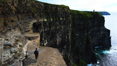 Aerial Shot Of Man Walking On Rocky Cliff Near Mountains, Drone Moving Forward - County Clare, Ireland