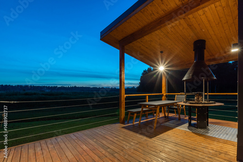 Outdoor dining area with a grill and a scenic view at dusk in a tranquil countryside setting