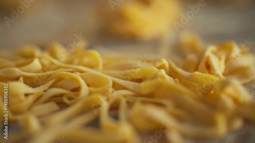 Freshly rolled pasta is spread out on a wooden surface, showcasing its delicate, thin strands. The cozy kitchen creates an inviting atmosphere for cooking