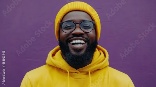 Obraz na płótnie Man in yellow hoodie and hat smiles warmly against a vibrant purple backdrop w salonie