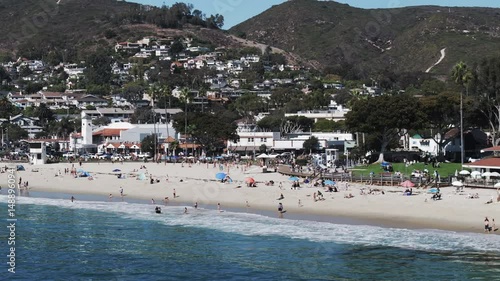 Aerial Panning Shot Of Male And Female Tourists At Beach In City, Drone Flying Over Wavy Sea On Sunny Day - Laguna Beach, California