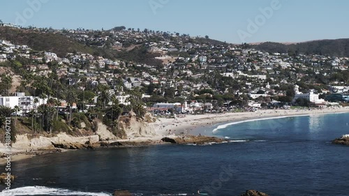 Aerial Panning Shot Of Tourists At Beach In Residential City On Hills During Sunny Day - Laguna Beach, California