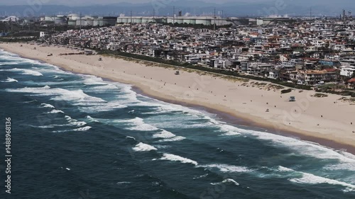 Aerial Panning Beautiful Shot Of Houses In Residential City, Drone Flying Over Wavy Sea On Sunny Day - Manhattan Beach, California