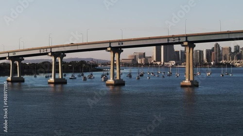 Aerial: Drone Panning Shot Of Cars Moving On Coronado Bridge In City, Drone Flying Over Rippled Sea - San Diego, California