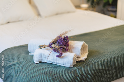 Towels on a bed in a hotel room with some flowers