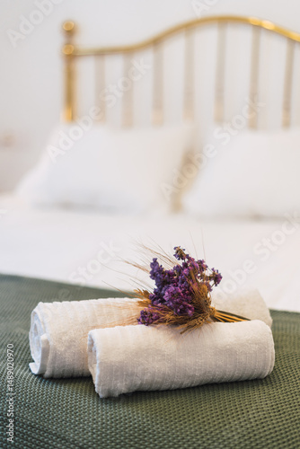 Towels on a bed in a hotel room with some flowers