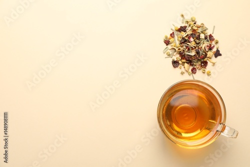 Fotografía Delicious herbal tea in glass cup and dry leaves on beige background, flat lay