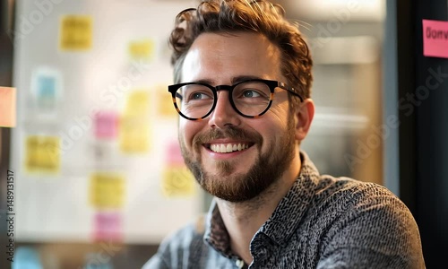 Portrait of a Smiling Bearded Man Wearing Glasses in Gray Shirt with Sticky Notes in the Background