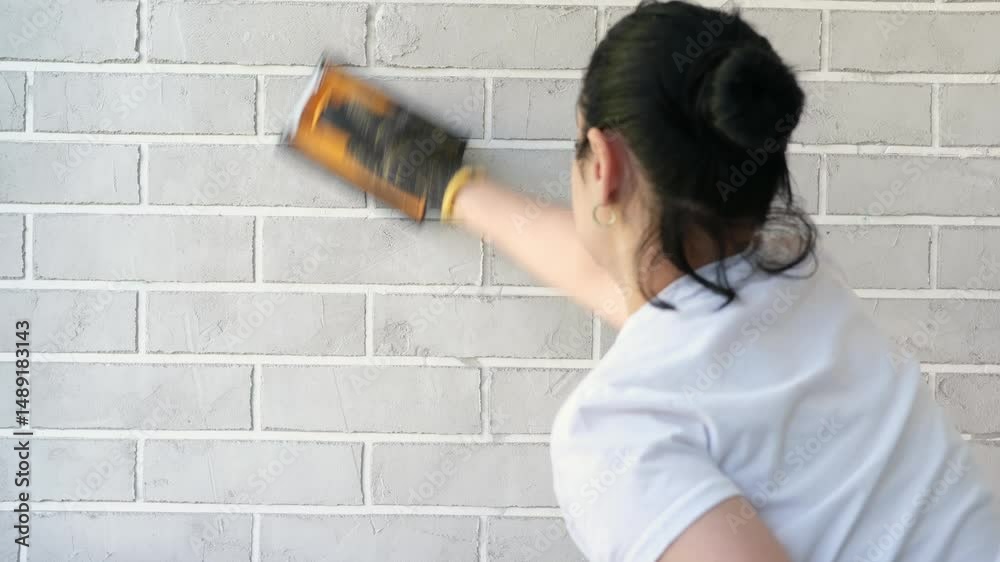 A woman's hand in a glove cleans a brick wall with sandpaper