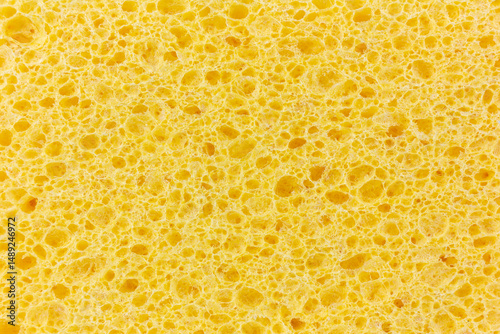 A close-up shot reveals the intricate, porous texture of a bright yellow cleaning sponge.