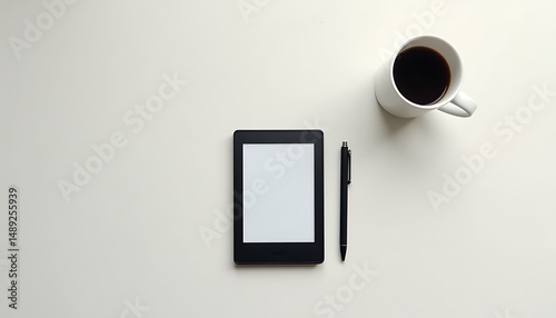 E reader coffee cup and pen on a white surface layout