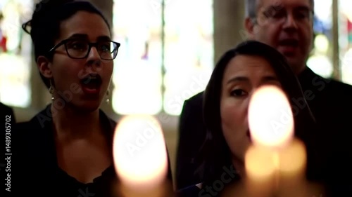 Group of people singing in a choir with candles in a church