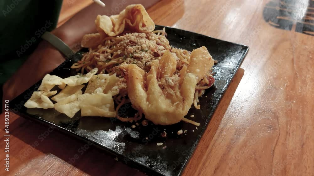 Crispy dumplings and savory noodles on a black plate