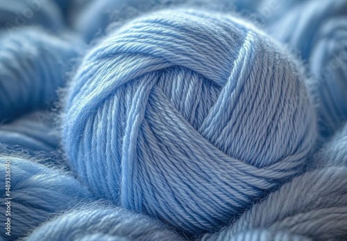 Close-up of a soft light blue yarn ball surrounded by loosely coiled yarn strands conveying warmth and coziness photo