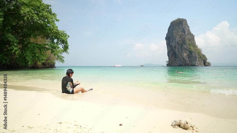 summer asian child sitting playing on white sand beach or kid girl wear swimsuit and goggles on blue sea with tourist diving at ko poda island in krabi thailand for people holiday vacation travel