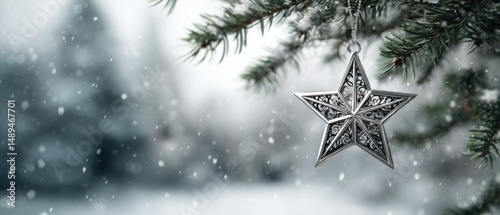 Silver christmas star ornament hanging from pine branch in winter snowfall