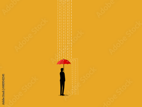 Businessman stands protecting himself with an umbrella from the rain