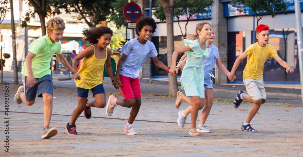 Obraz premium Group of smiling kids holding each other hands while running through city streets together.