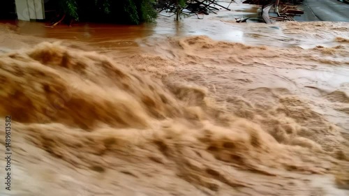 Powerful floodwaters inundate buildings and vehicles, flowing through a neighborhood during severe weather event