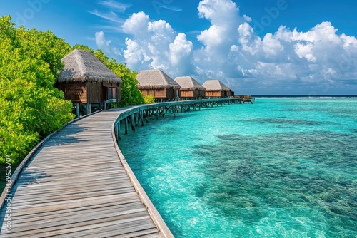 Tropical overwater bungalows on a pristine beach. Lush vegetation surrounds a wooden walkway extending to the turquoise ocean