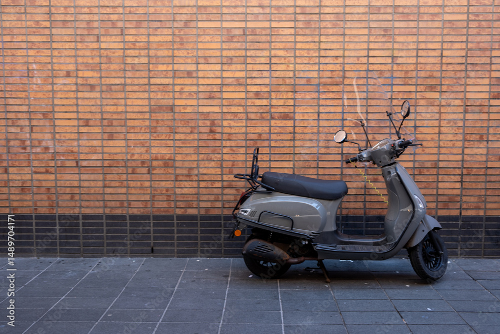 Scooter vintage motor parked on a sidewalk, in front of a brick wall,