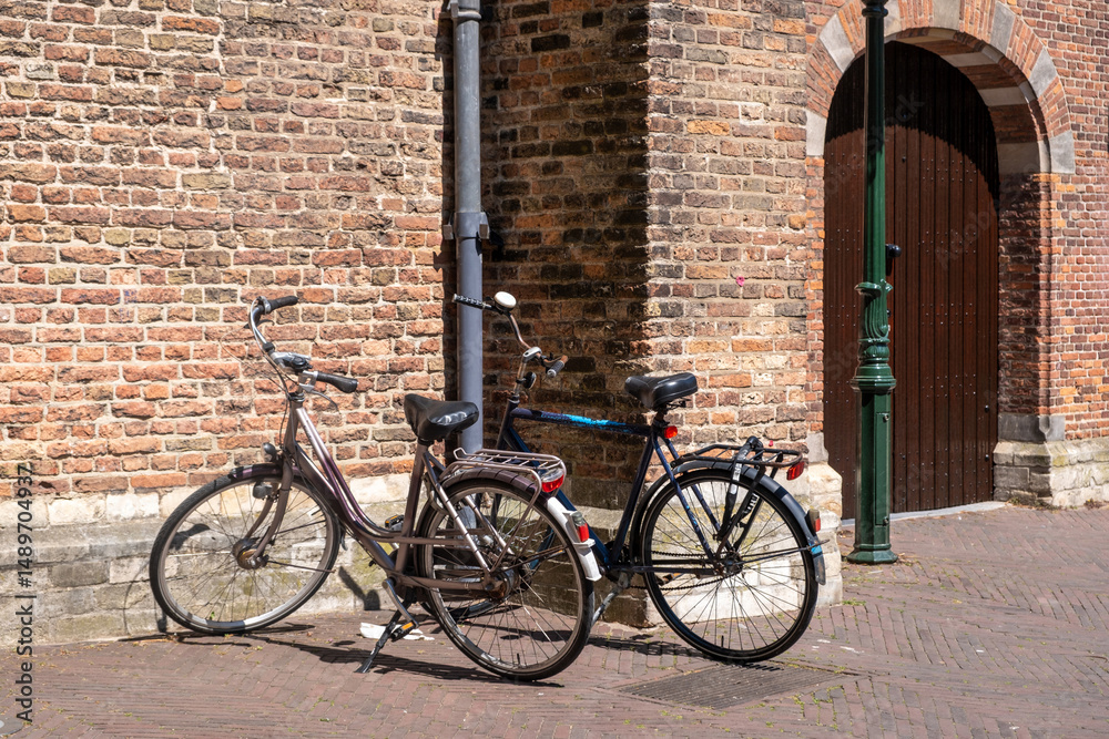 Bicycles parked on sidewalk in front of brickwall building in Holland. Biking in Netherlands