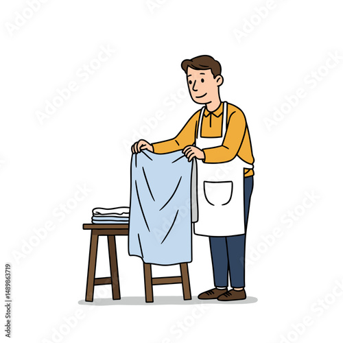 Man folding laundry with a smile while wearing an apron at the table