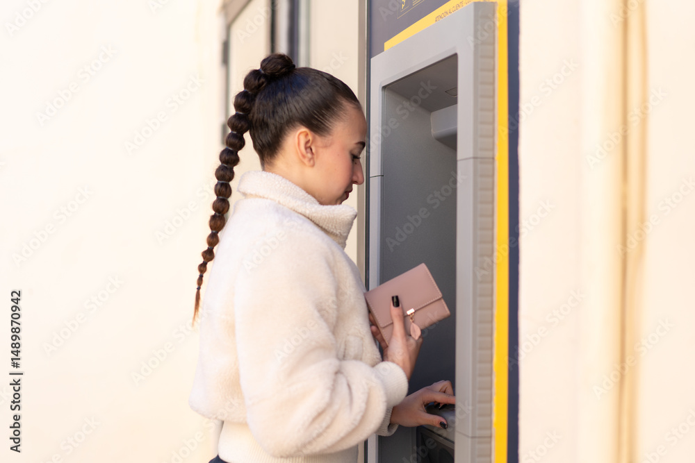 Young moroccan girl at outdoors using an ATM Young moroccan girl at outdoors using an ATM