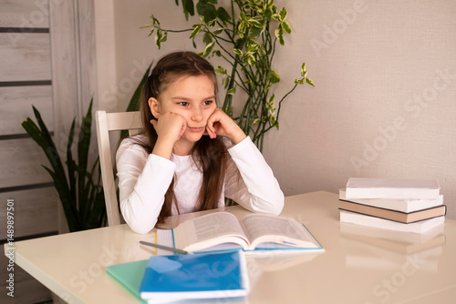 Little schoolgirl is upset and depressed. Depressed girl does not want to study, she has poor grades at school. Schoolgirl is tired in class and wants to sleep. Concept of education.