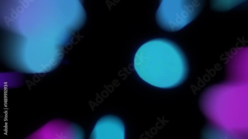 Abstract animation of soft, blurred blue and pink bokeh lights. Defocused circular shapes move and float on black background