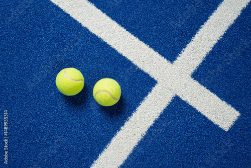 Close-up of a blue padel court showing clean white lines and bright yellow balls.